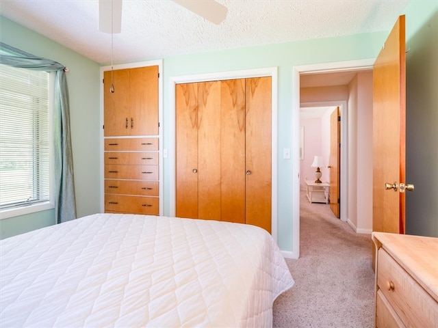 carpeted bedroom featuring a closet, ceiling fan, and a textured ceiling