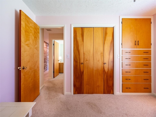 hall featuring light carpet and a textured ceiling