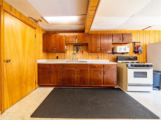 kitchen with wood walls, white appliances, and sink