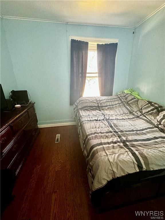 bedroom with ornamental molding and dark hardwood / wood-style floors