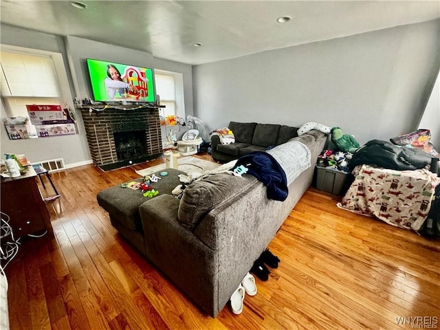 living room featuring plenty of natural light, hardwood / wood-style floors, and a brick fireplace