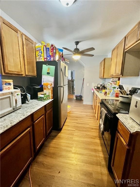 kitchen with range with electric stovetop, light stone counters, ceiling fan, and light hardwood / wood-style floors