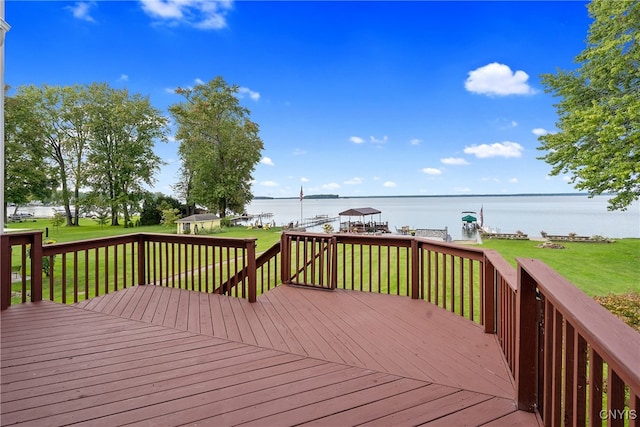 wooden deck with a water view and a lawn