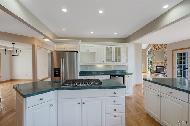 kitchen featuring a fireplace, light hardwood / wood-style flooring, a center island, stainless steel appliances, and white cabinets