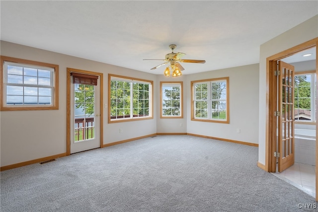 empty room featuring ceiling fan, light carpet, and a healthy amount of sunlight