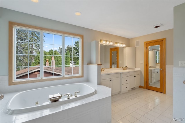 bathroom with tile patterned floors, tiled tub, and vanity