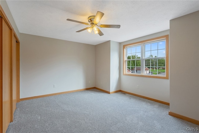 unfurnished bedroom featuring a textured ceiling, light colored carpet, ceiling fan, and a closet