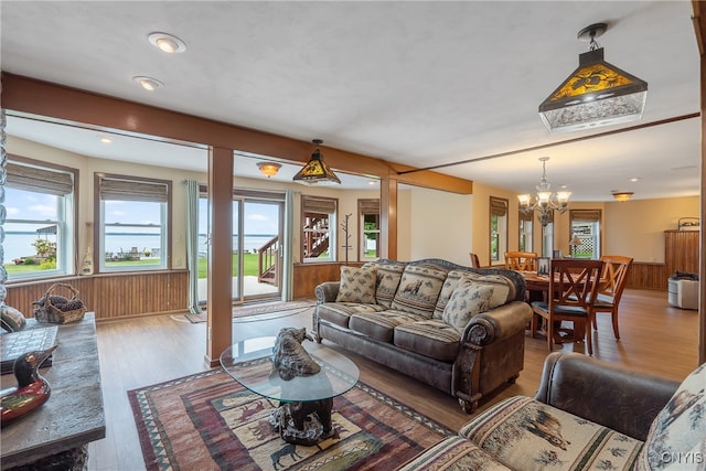 living room featuring a notable chandelier, hardwood / wood-style flooring, and wooden walls