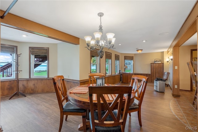 dining space with a healthy amount of sunlight, an inviting chandelier, hardwood / wood-style floors, and wooden walls