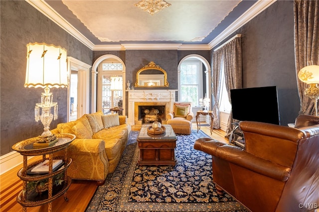 living room featuring wood-type flooring, a fireplace, and crown molding