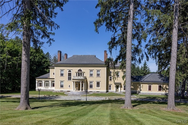 colonial inspired home with a balcony and a front yard