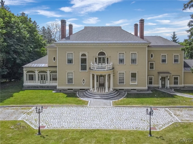 back of house with a lawn and a balcony