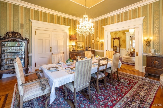 dining space with ornamental molding, a notable chandelier, and hardwood / wood-style flooring