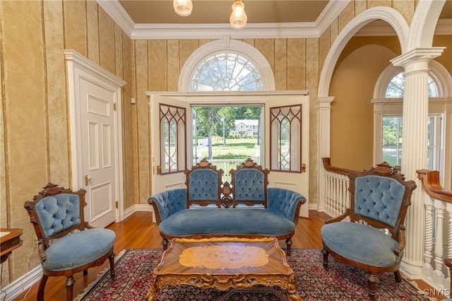 sitting room featuring ornamental molding, wood-type flooring, and decorative columns