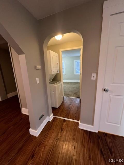 hallway featuring stacked washer / dryer and dark hardwood / wood-style floors