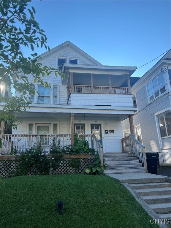 view of front of property with a balcony, a front yard, and a porch