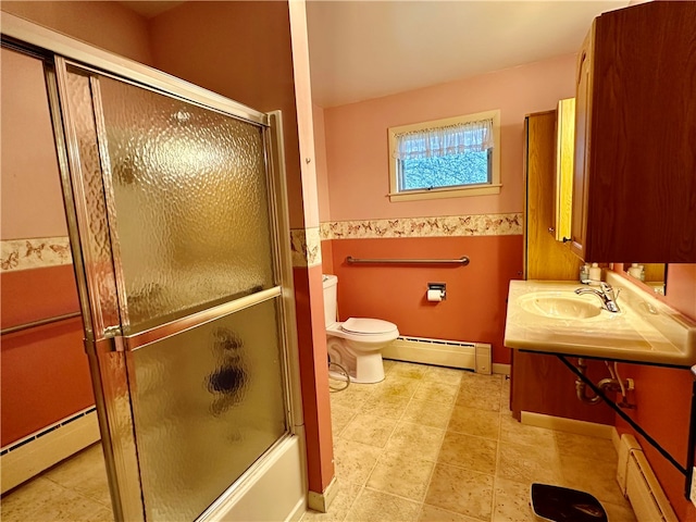 full bathroom with bath / shower combo with glass door, baseboard heating, and sink