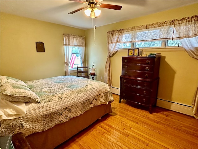 bedroom featuring multiple windows, ceiling fan, light hardwood / wood-style floors, and a baseboard radiator