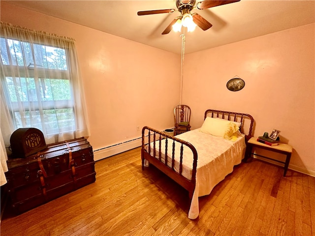 bedroom featuring light hardwood / wood-style flooring, ceiling fan, and a baseboard heating unit