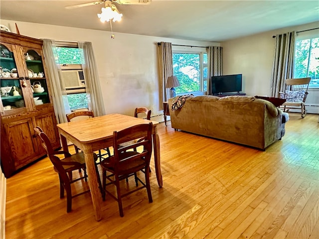 dining area with light wood-type flooring, a baseboard radiator, ceiling fan, and a healthy amount of sunlight