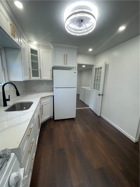 kitchen featuring white cabinets, white refrigerator, light stone counters, sink, and dark wood-type flooring