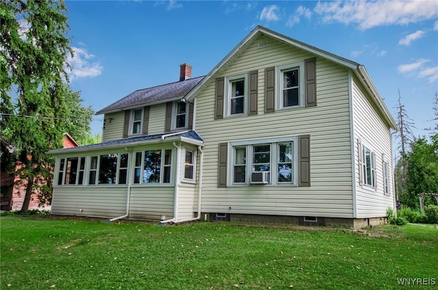 back of property featuring a sunroom and a lawn