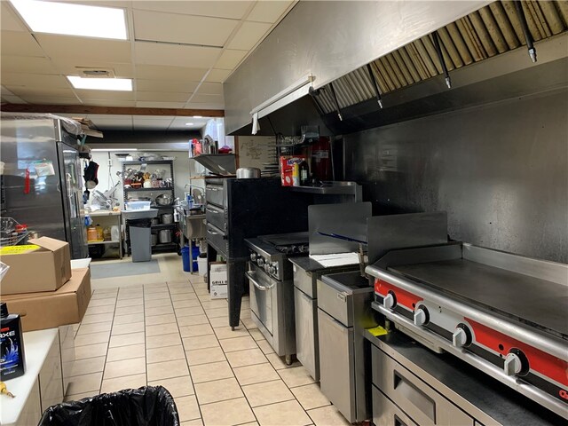 kitchen featuring a drop ceiling, light tile patterned floors, and stainless steel range