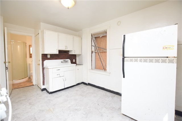 kitchen with decorative backsplash, white refrigerator, sink, and white cabinets