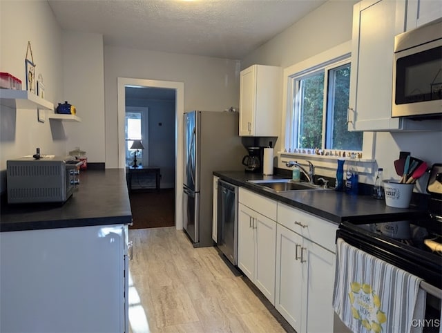 kitchen featuring a textured ceiling, sink, appliances with stainless steel finishes, and white cabinetry