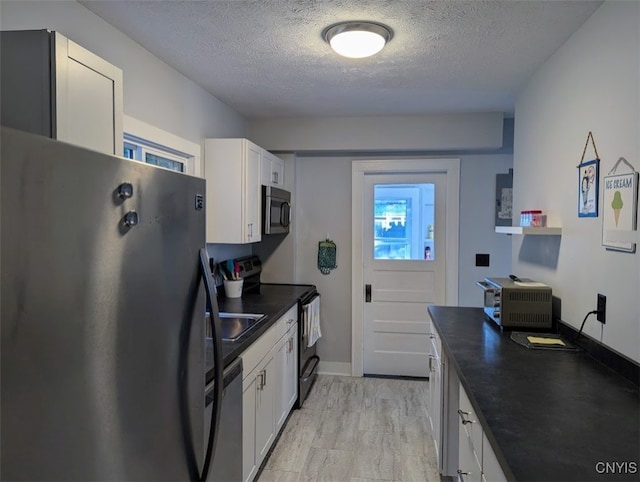 kitchen with stainless steel appliances, white cabinetry, and a textured ceiling