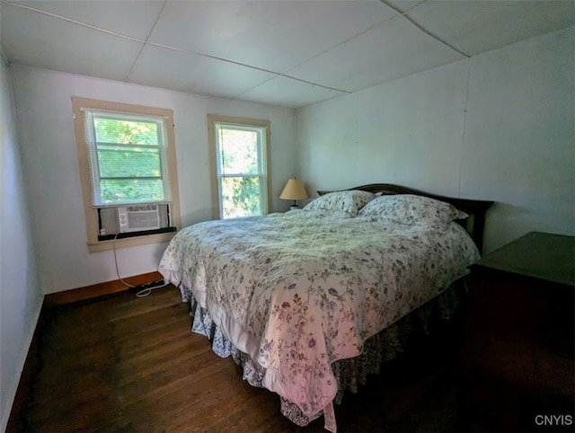 bedroom featuring dark wood-type flooring, cooling unit, and a drop ceiling