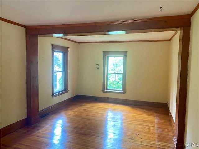 spare room featuring light wood-type flooring and crown molding