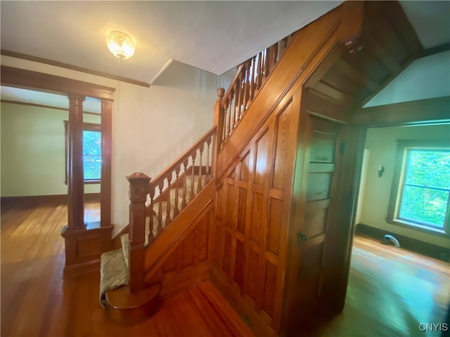 staircase featuring wood-type flooring and decorative columns