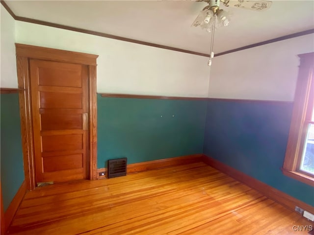 empty room with crown molding, ceiling fan, and wood-type flooring