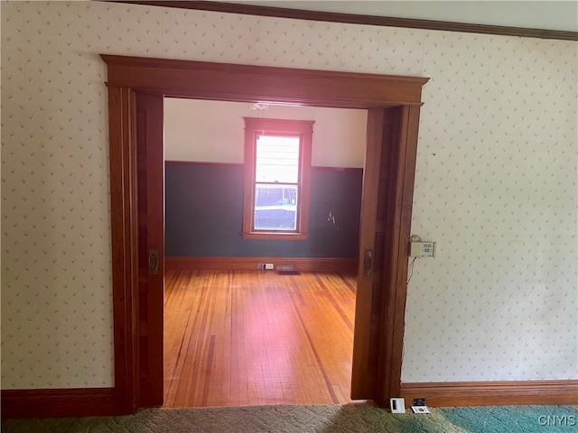 corridor with crown molding and wood-type flooring