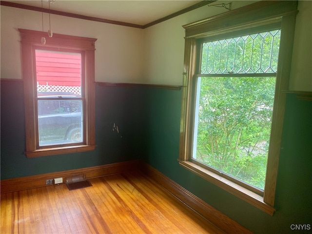 spare room featuring crown molding and light hardwood / wood-style floors