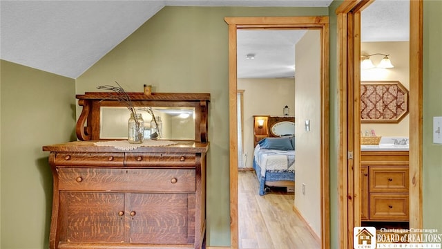 interior space featuring lofted ceiling, light hardwood / wood-style flooring, sink, and a textured ceiling