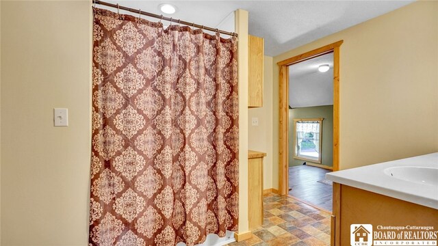 bathroom with vanity, a textured ceiling, hardwood / wood-style floors, and curtained shower