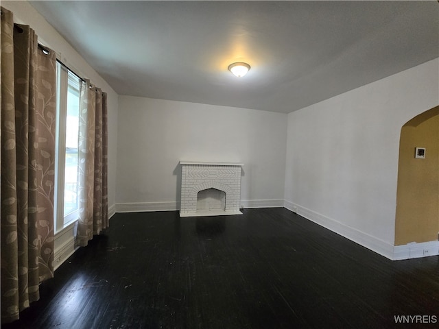 unfurnished living room with dark hardwood / wood-style floors and a brick fireplace