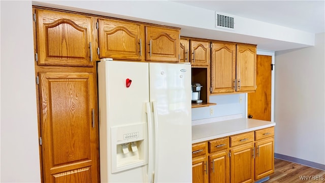 kitchen featuring wood-type flooring and white fridge with ice dispenser