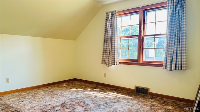 additional living space with vaulted ceiling and dark colored carpet