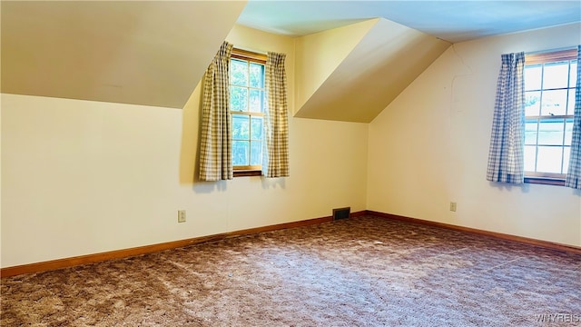 additional living space featuring dark carpet and lofted ceiling