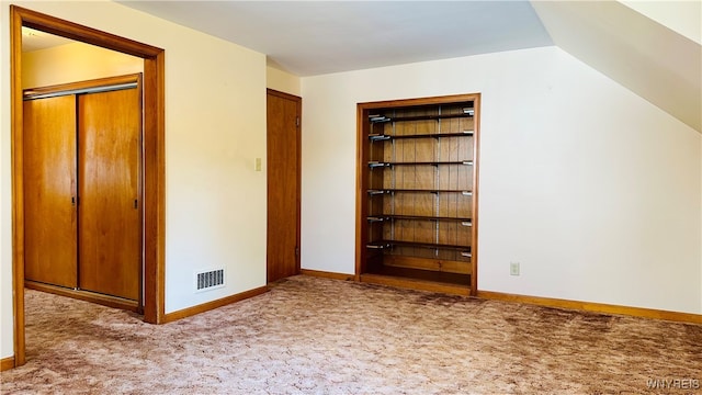 bonus room with built in features, vaulted ceiling, and light carpet