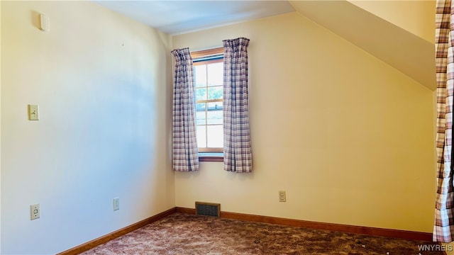 carpeted empty room with vaulted ceiling