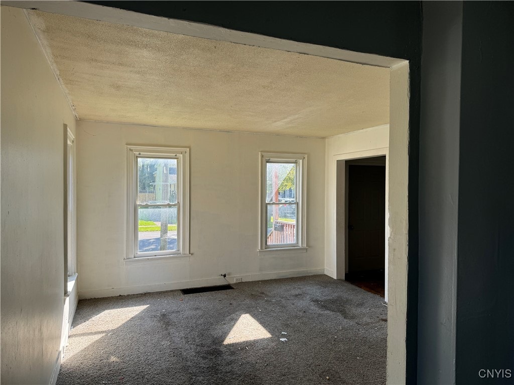 empty room featuring a textured ceiling and carpet flooring