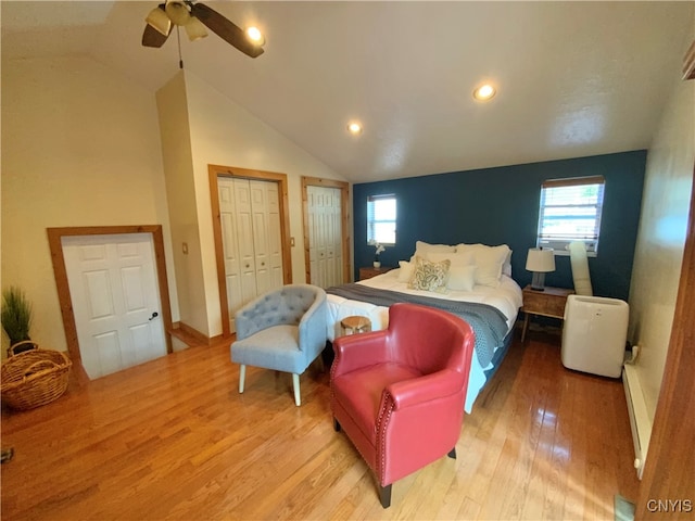 bedroom with multiple closets, vaulted ceiling, hardwood / wood-style floors, and ceiling fan