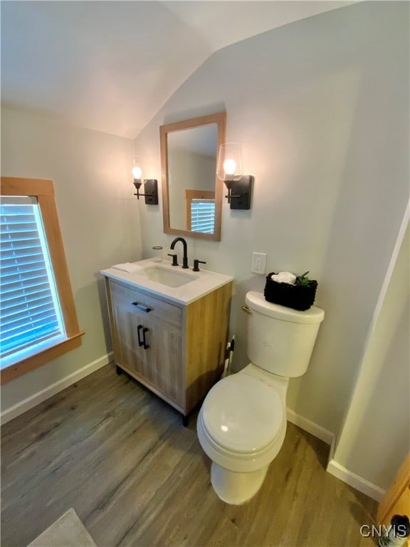 bathroom with lofted ceiling, wood-type flooring, toilet, and vanity