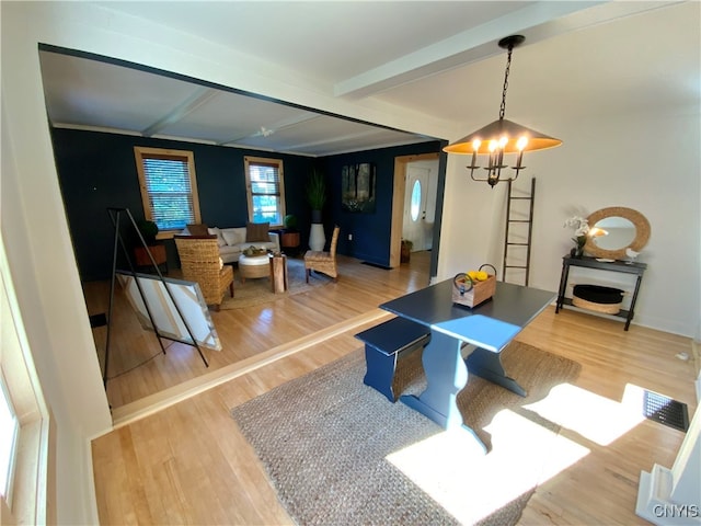 living room with a notable chandelier, beamed ceiling, and light hardwood / wood-style floors