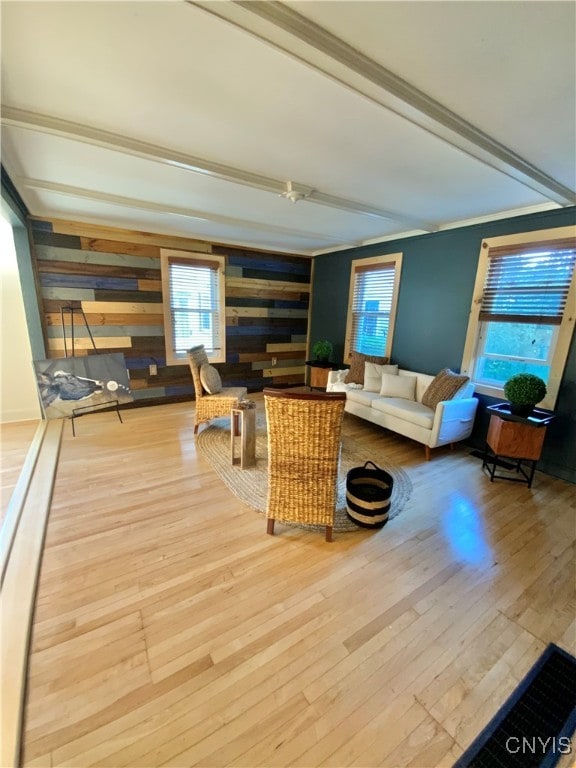 living room featuring ornamental molding, beamed ceiling, hardwood / wood-style floors, and wooden walls