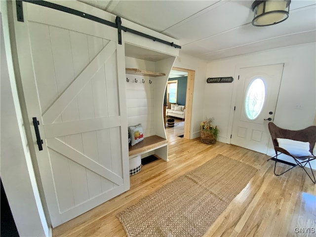 foyer entrance with a barn door and light hardwood / wood-style flooring